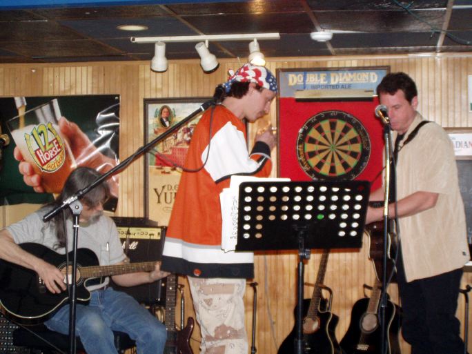 Dean shoots darts while the band plays on